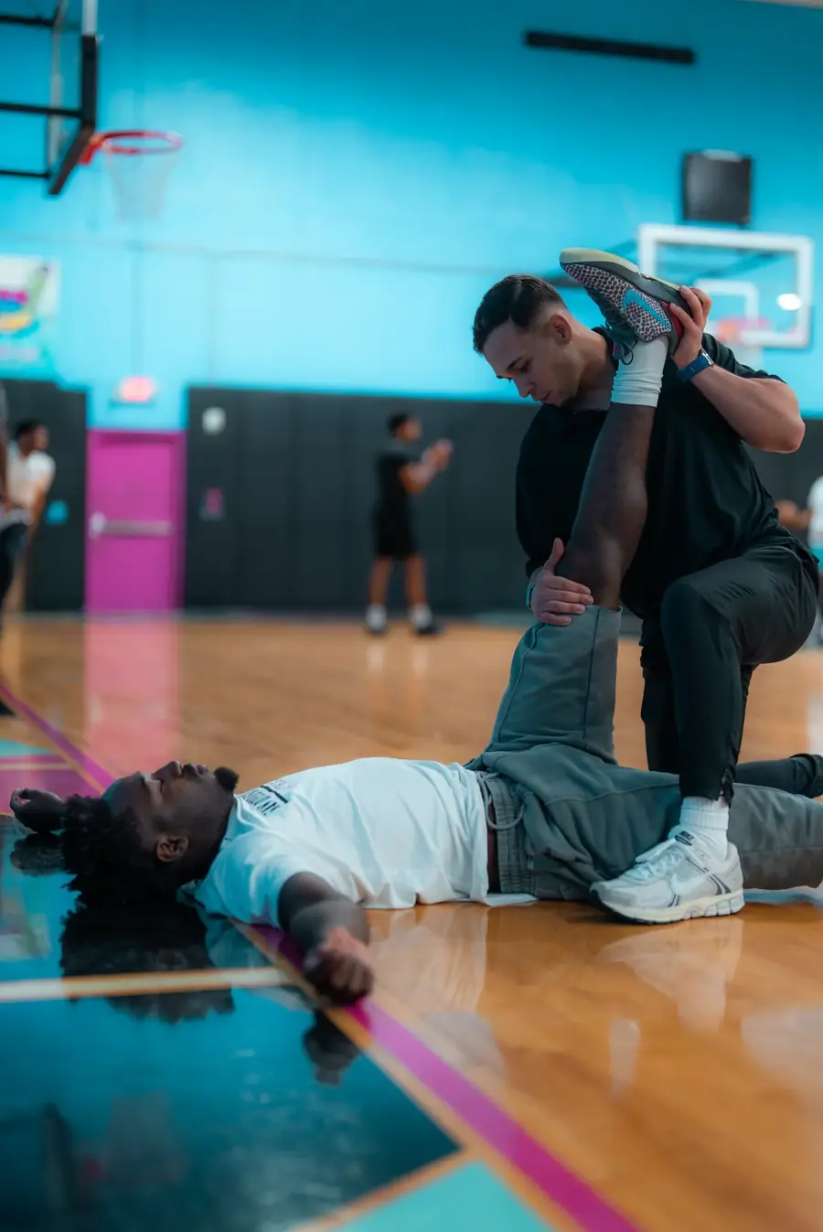 Dr. Sierra stretching Darrion Trammell's hip on a basketball court