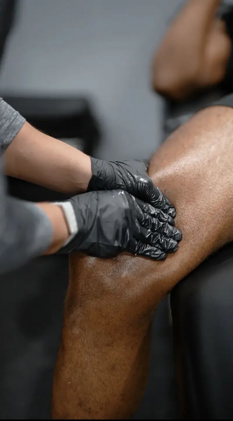 Gloved hands performing soft tissue work on a knee
